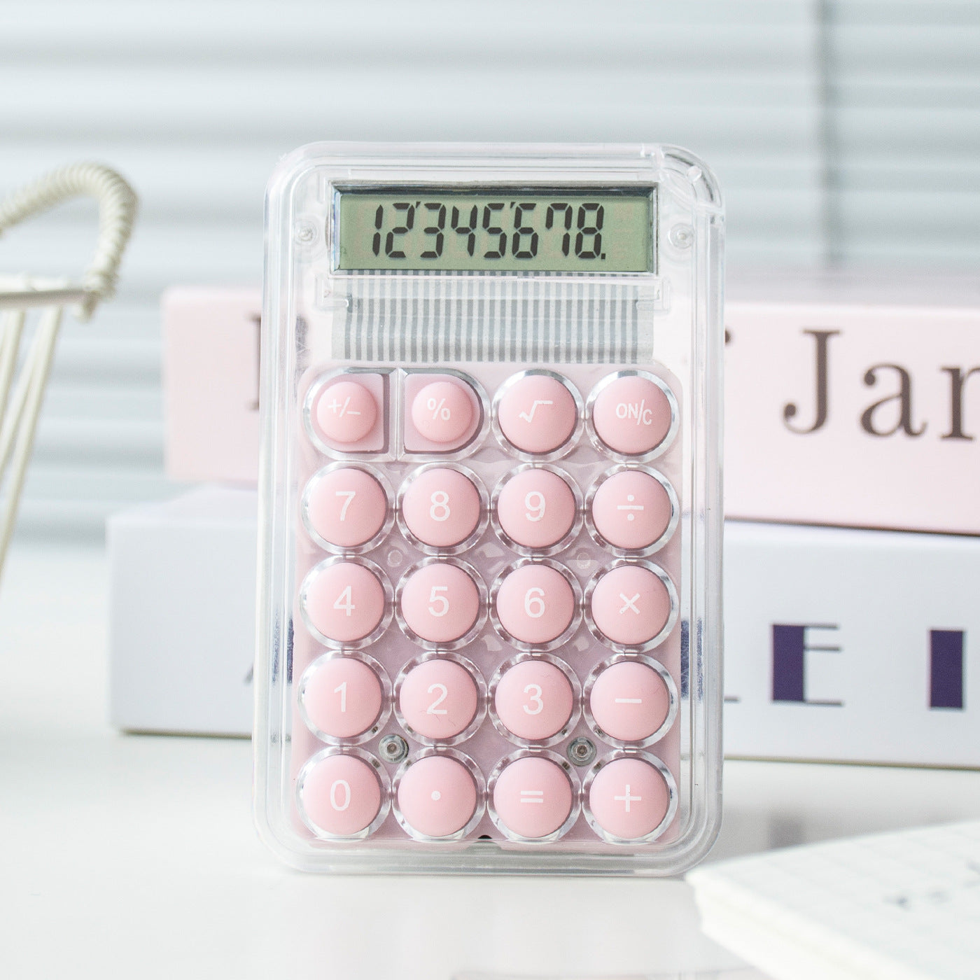 Pink calculator with a clear plastic cover on a white surface