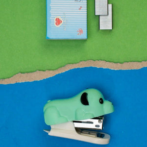 Green stapler and staples on a blue and green background