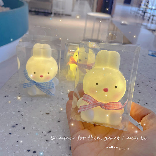 Two small yellow rubber duck toys in clear packaging held by a hand on a speckled surface.