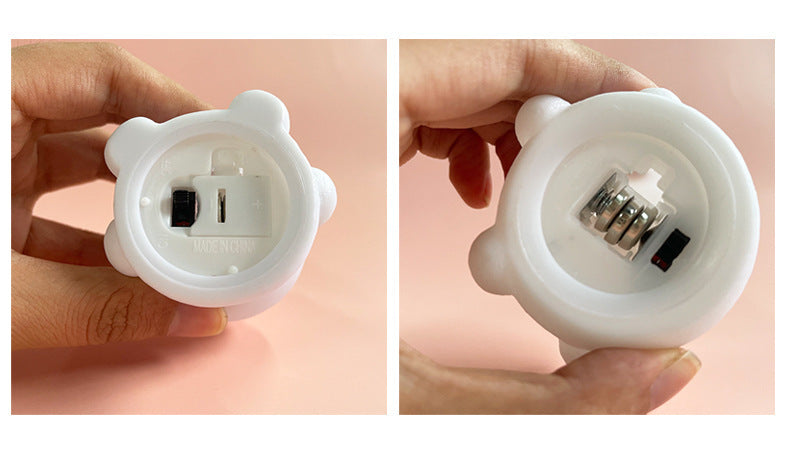 Close-up of a white light bulb socket held by a hand against a pink background
