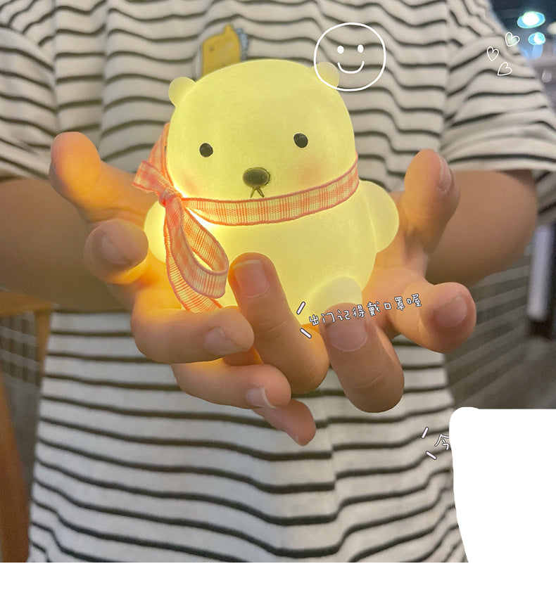 Person holding a glowing yellow bear-shaped object with a striped shirt.