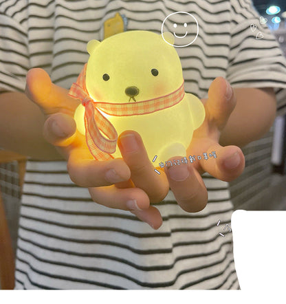 Person holding a glowing yellow bear-shaped object with a striped shirt.