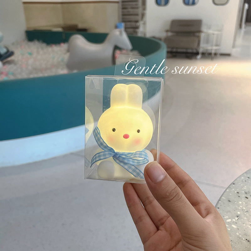 Hand holding a small lamp with a cartoon character in a clear package, labeled 'Gentle sunset'.