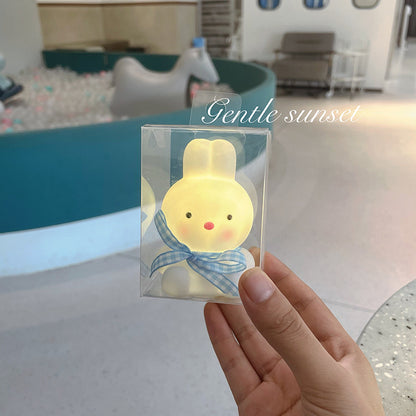 Hand holding a small lamp with a cartoon character in a clear package, labeled 'Gentle sunset'.