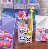 Set of colorful stationery items including pens, markers, and a small box on a wooden surface.