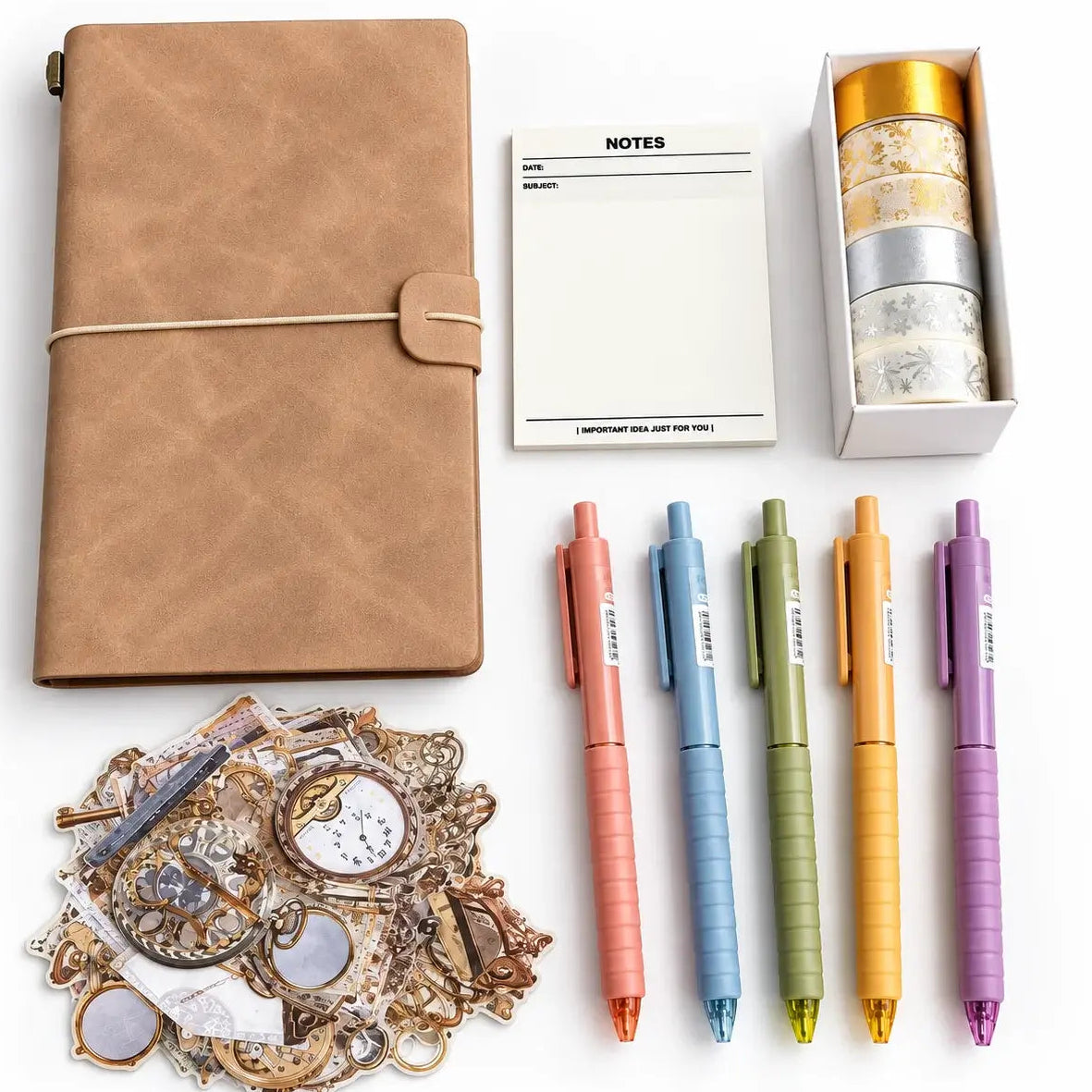 A stationery gift set arranged on a white background, including a tan leather-look notebook with a rope closure, a small white notes pad, a box of patterned washi tapes, five colorful retractable pens in pink, blue, green, yellow, and purple, and a pile of decorative vintage-style stickers.