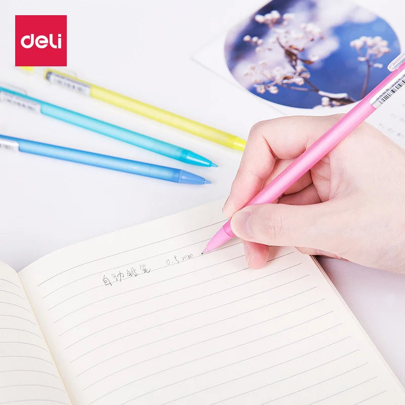 Hand holding a pink pen over an open notebook with Deli branding visible.