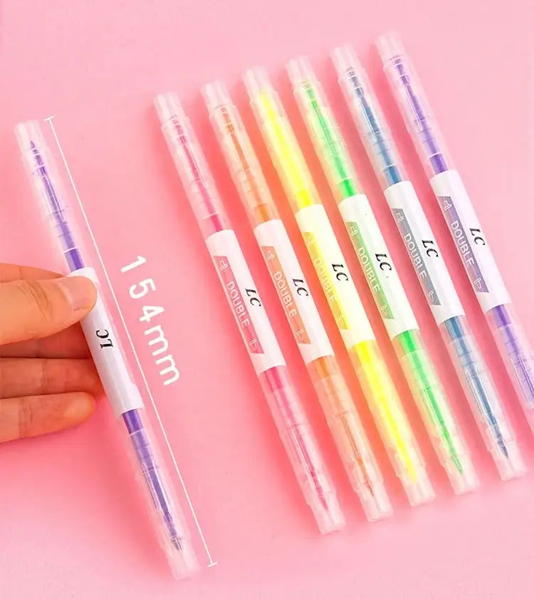 Set of colorful gel pens with a hand holding one pen on a pink background