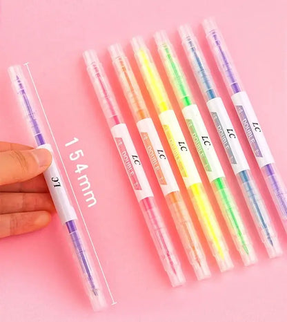 Set of colorful gel pens with a hand holding one pen on a pink background