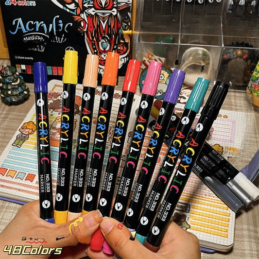 Set of acrylic paint markers held by a hand with a colorful background