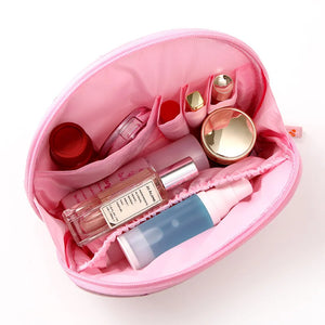 Pink cosmetic bag with various beauty products on a white background