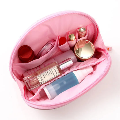 Pink cosmetic bag with various beauty products on a white background