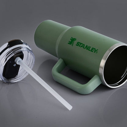 Green Stanley tumbler with a straw on a gray background