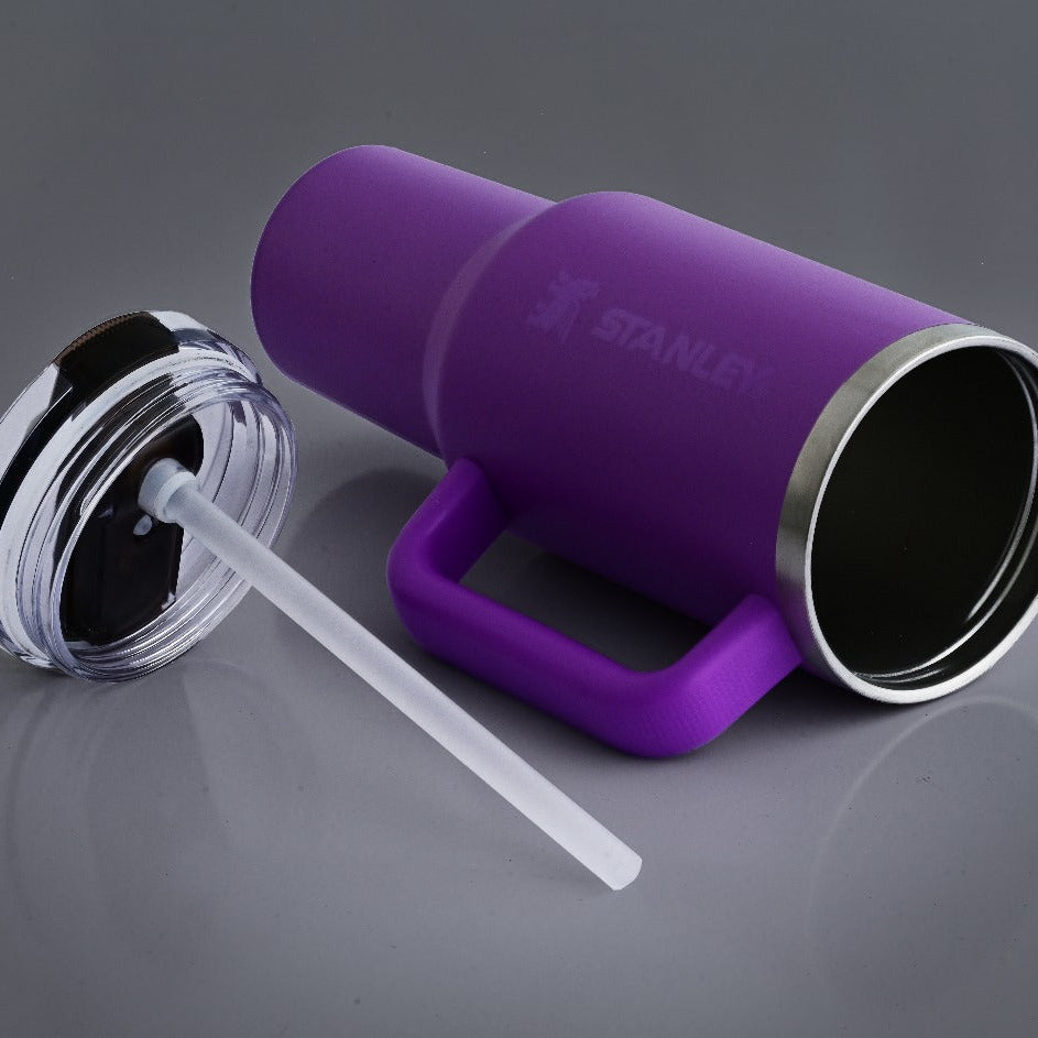Purple Stanley tumbler with a clear straw on a gray background