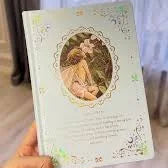 Hand holding a decorative card with a floral design and text.