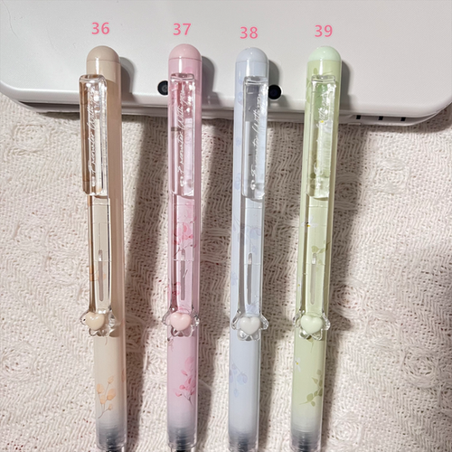 Four pens with different designs and colors on a textured surface