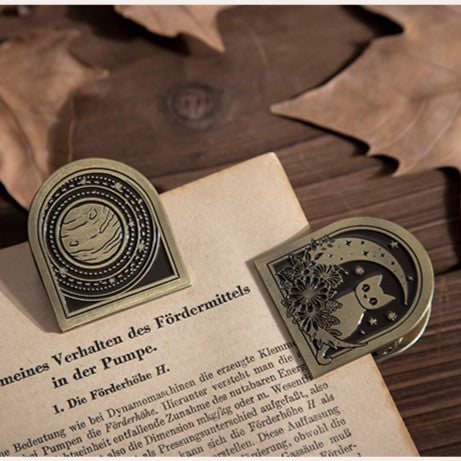 Decorative metal bookmarks with moon and star design on an open book.