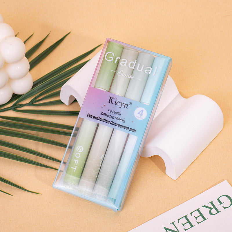 Pack of Kicyn gradient pens on a beige background with green leaves and a white object.