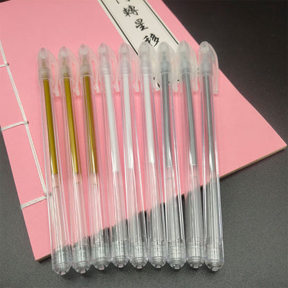 Set of clear gel pens with gold and black accents on a pink notebook background