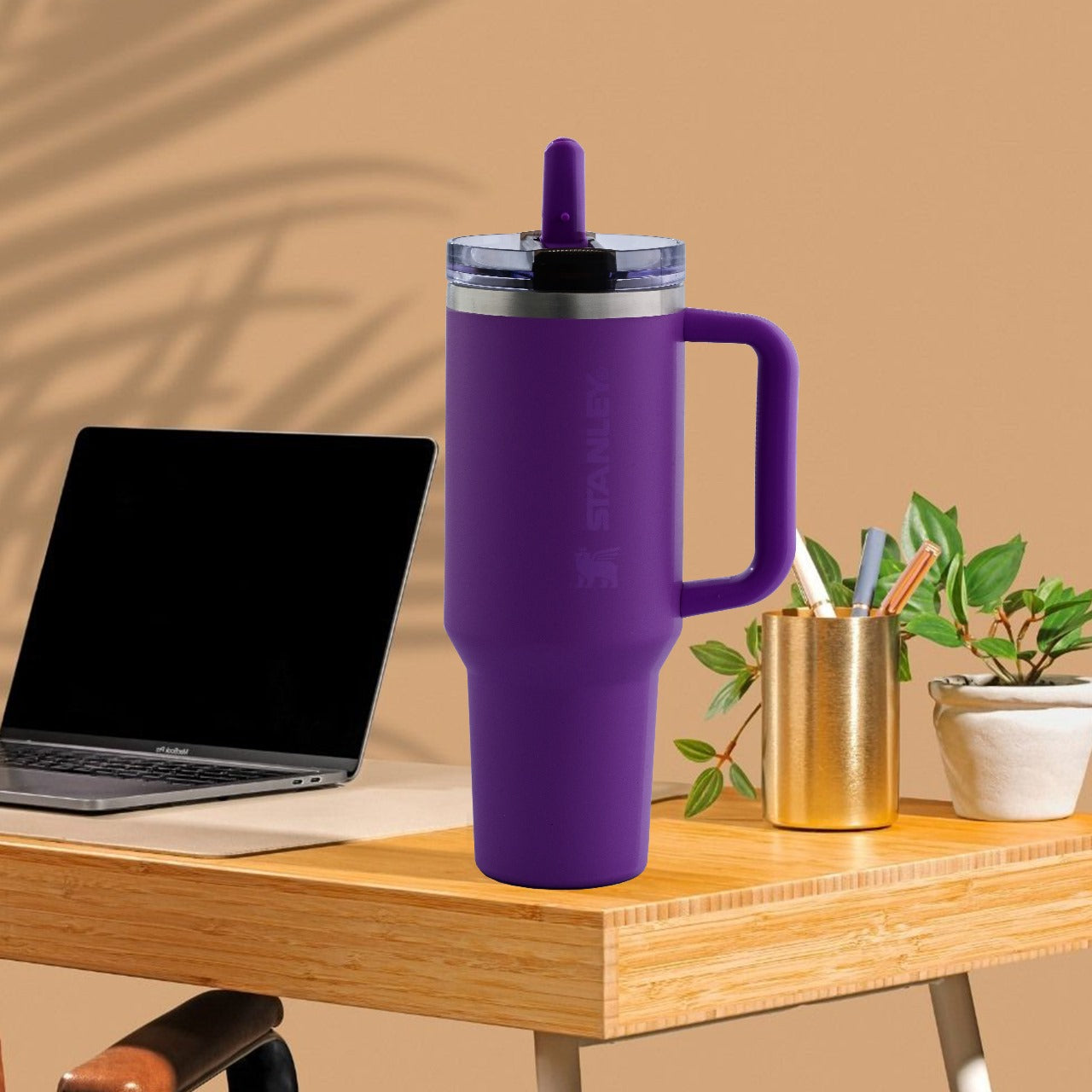 Purple mug with handle on a wooden desk with laptop and office supplies