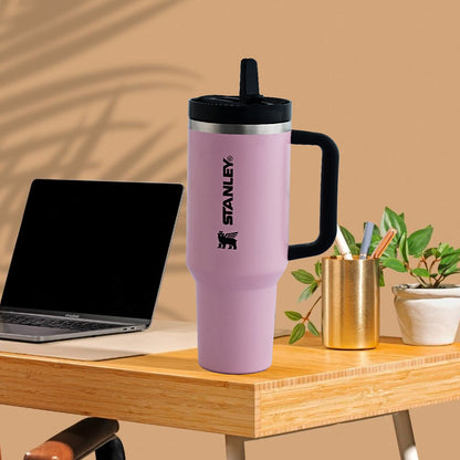 Pink Stanley tumbler on a desk with a laptop and office supplies.