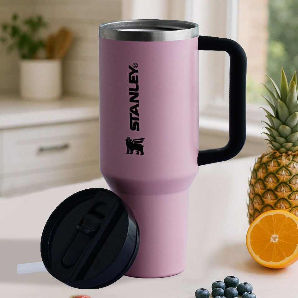 Pink Stanley mug with black handle on a kitchen counter with fruit