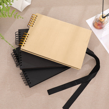 Three spiral-bound notebooks in beige, black, and dark brown on a beige surface with a black strap.