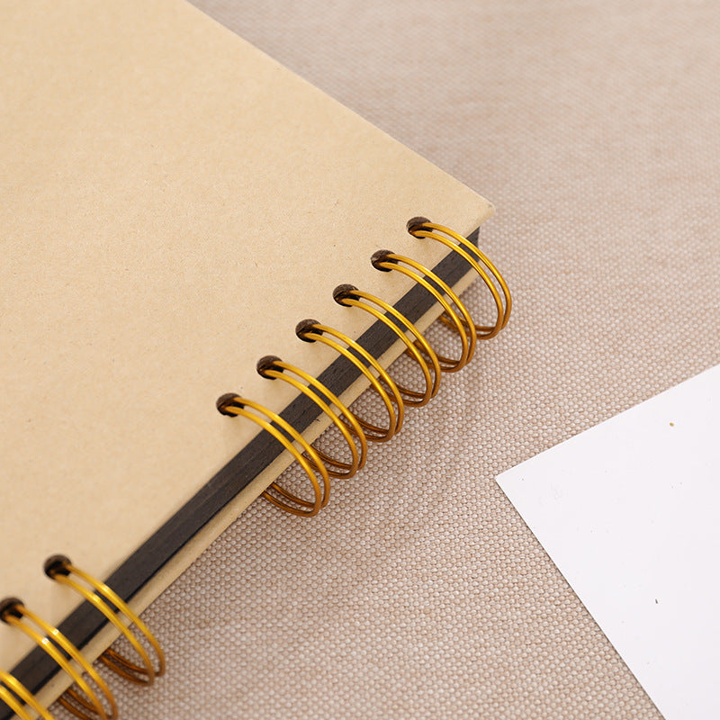 Beige notebook with gold spiral binding on a beige fabric background