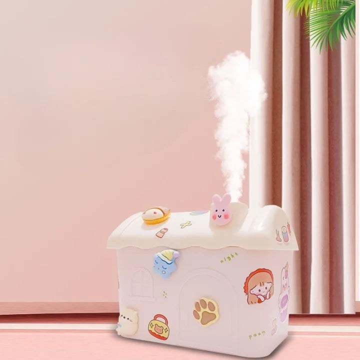 A white and transparent house-shaped fog humidifier with a rabbit 3D sticker, emitting a mist, placed in a room with a pink wall and curtains.
