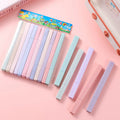 Set of pastel-colored markers with a colorful box on a pink background