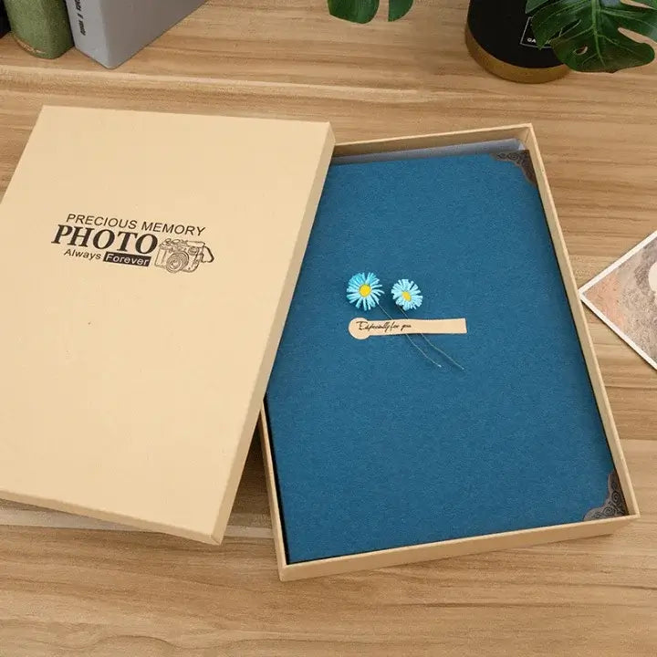 Blue photo album with floral design in a wooden box on a wooden surface