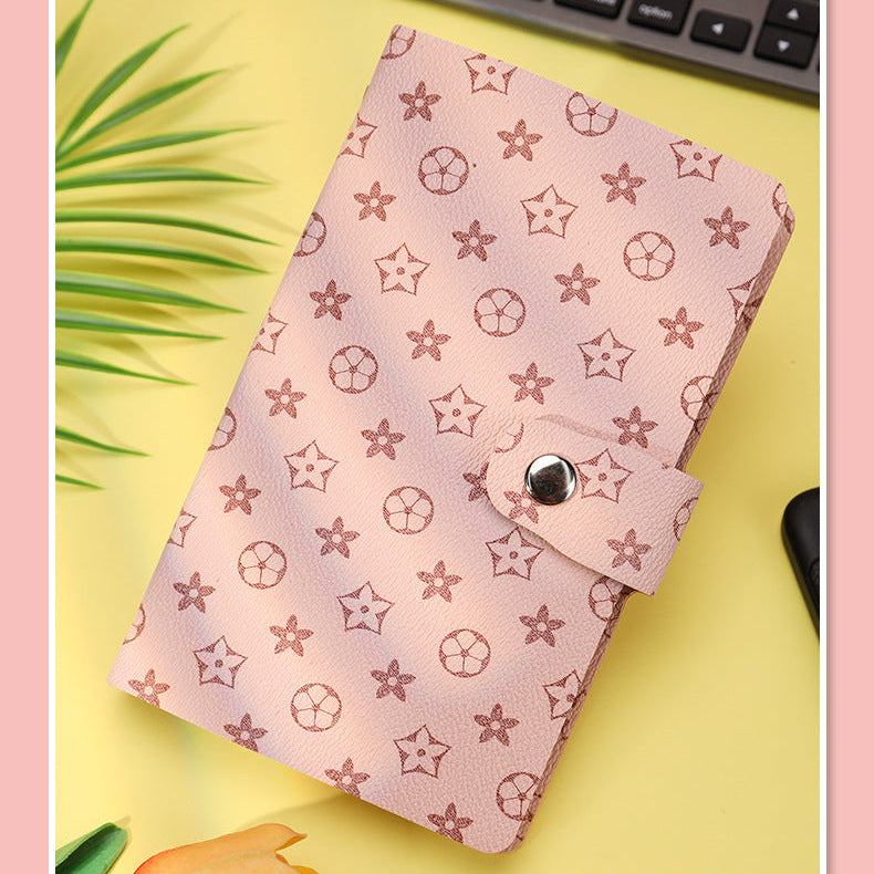Pink notebook with star pattern on a yellow surface with keyboard and plant