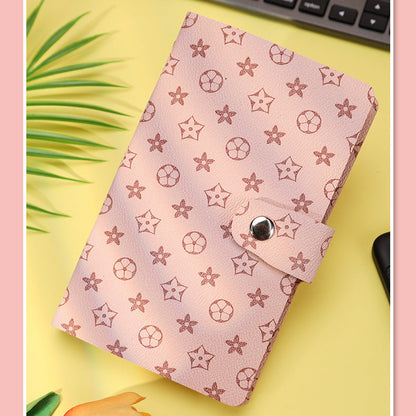 Pink notebook with star pattern on a yellow surface with keyboard and plant