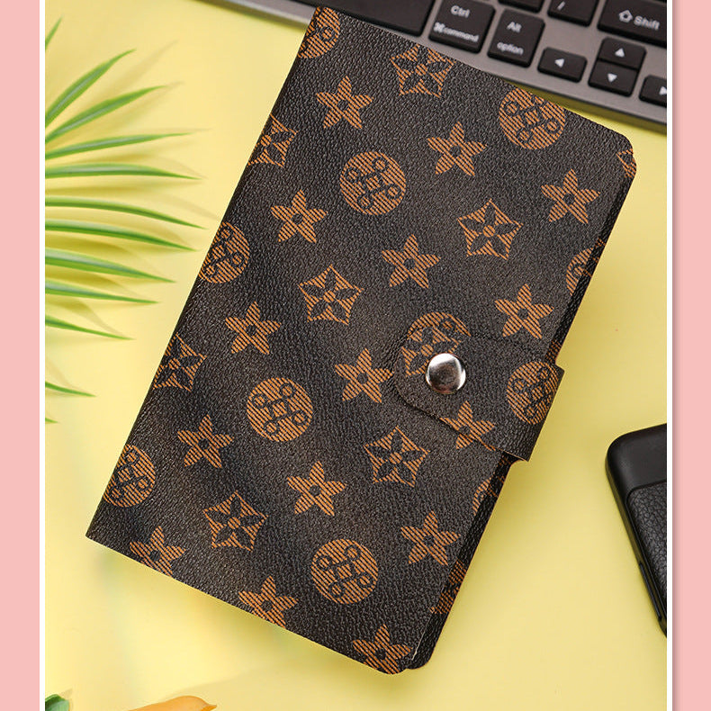 Brown patterned wallet on a yellow surface with a keyboard in the background