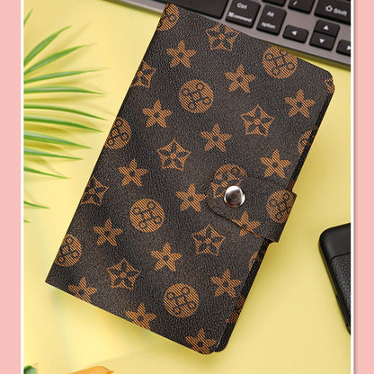 Brown patterned wallet on a yellow surface with a keyboard in the background