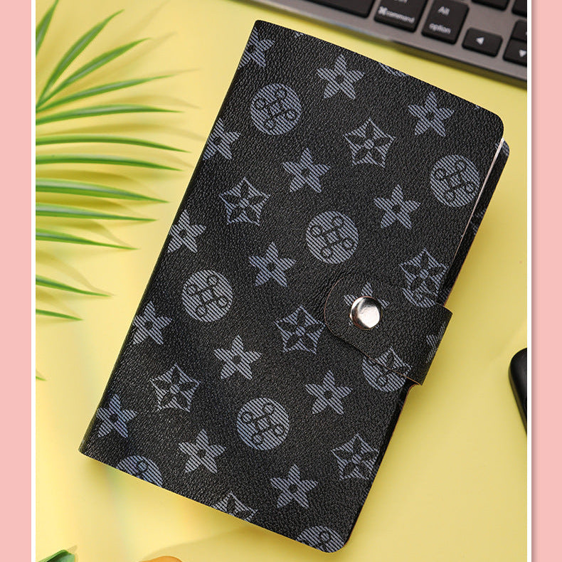 Black patterned notebook on a yellow surface with a keyboard in the background