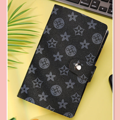 Black patterned notebook on a yellow surface with a keyboard in the background