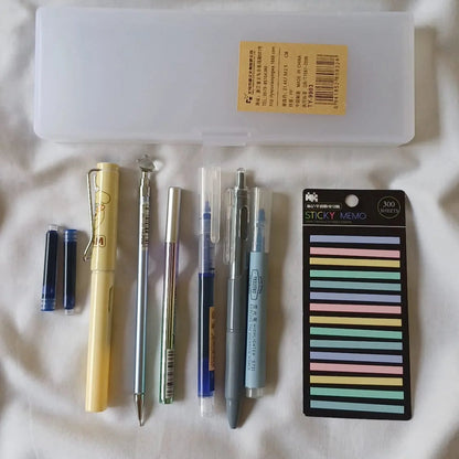 Collection of stationery items including pens and a sticky notes pack on a white surface