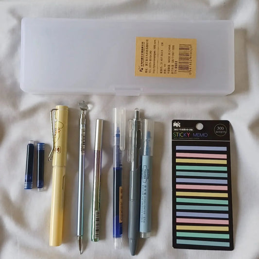 Collection of stationery items including pens, a highlighter, and sticky notes on a white surface.
