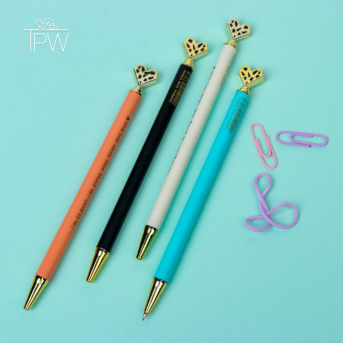A set of mechanical pencils with heart-shaped tops and butterfly details, displayed in a variety of colors including black, white, orange, and blue. Accompanied by pink paper clips on a light blue background.