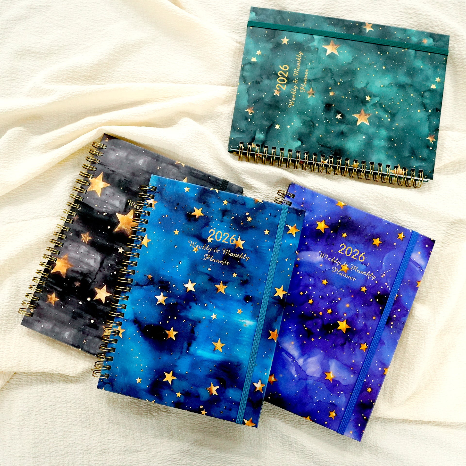 Set of spiral-bound planners with star design on a white fabric background