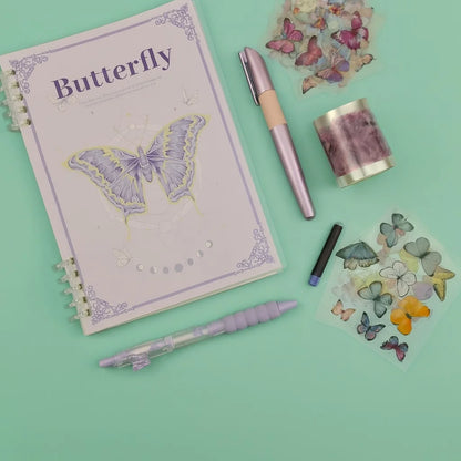 Notebook with butterfly design, pens, and butterfly stickers on a green background