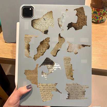 Gray tablet case with cut-out designs resembling old paper and text on a wooden surface.