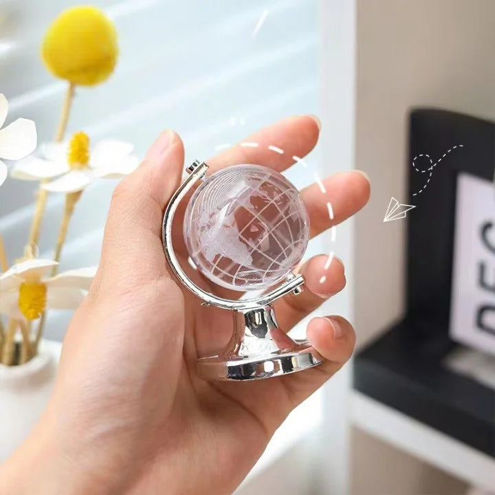 Hand holding a small globe with a blurred indoor background
