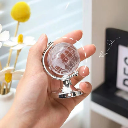 Hand holding a small globe with a blurred indoor background