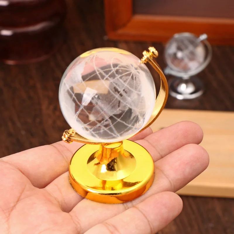 Small globe with gold base held in a hand against a blurred background