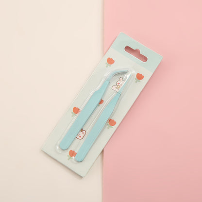 Pair of blue tweezers in packaging on a pink and beige background