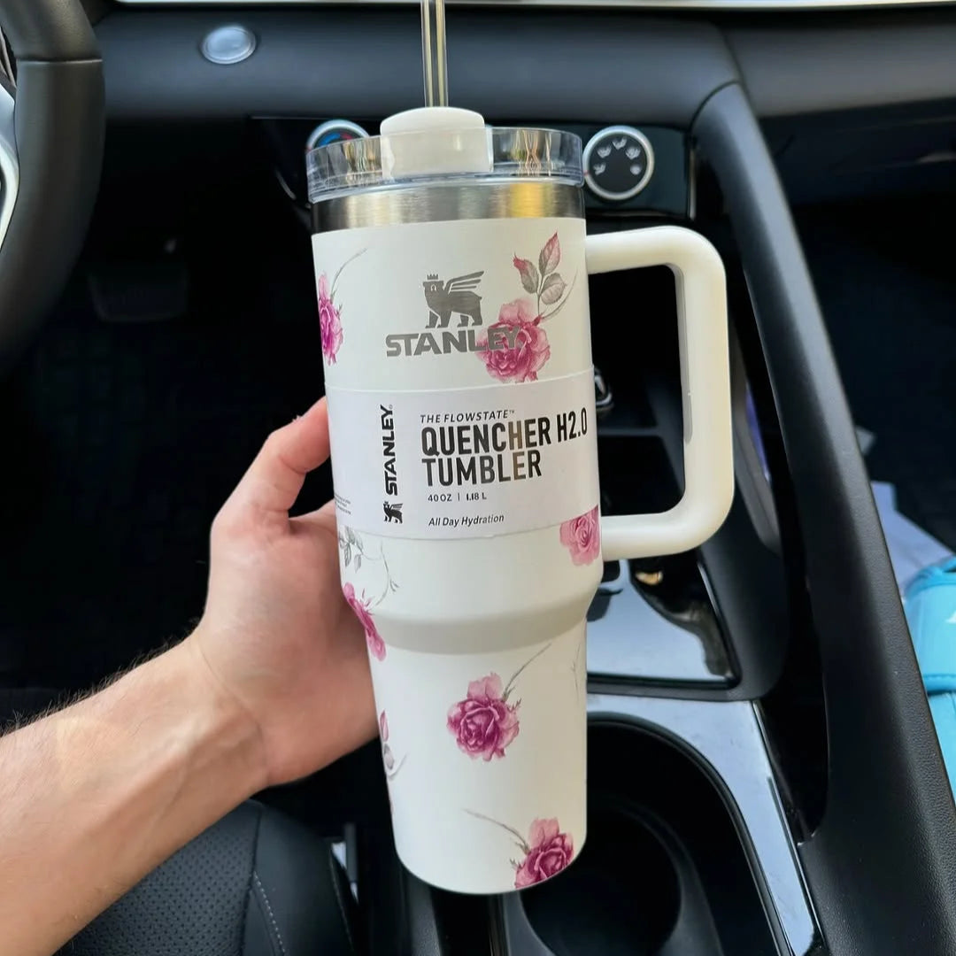 Person holding a floral Stanley tumbler in a car.