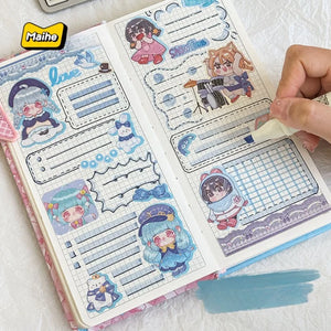 Notebook with cute character stickers and a hand holding it, featuring the brand 'Maihe'.