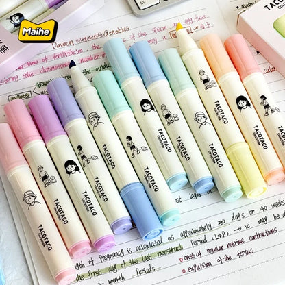 Set of colorful markers with cartoon character design on a notebook page.